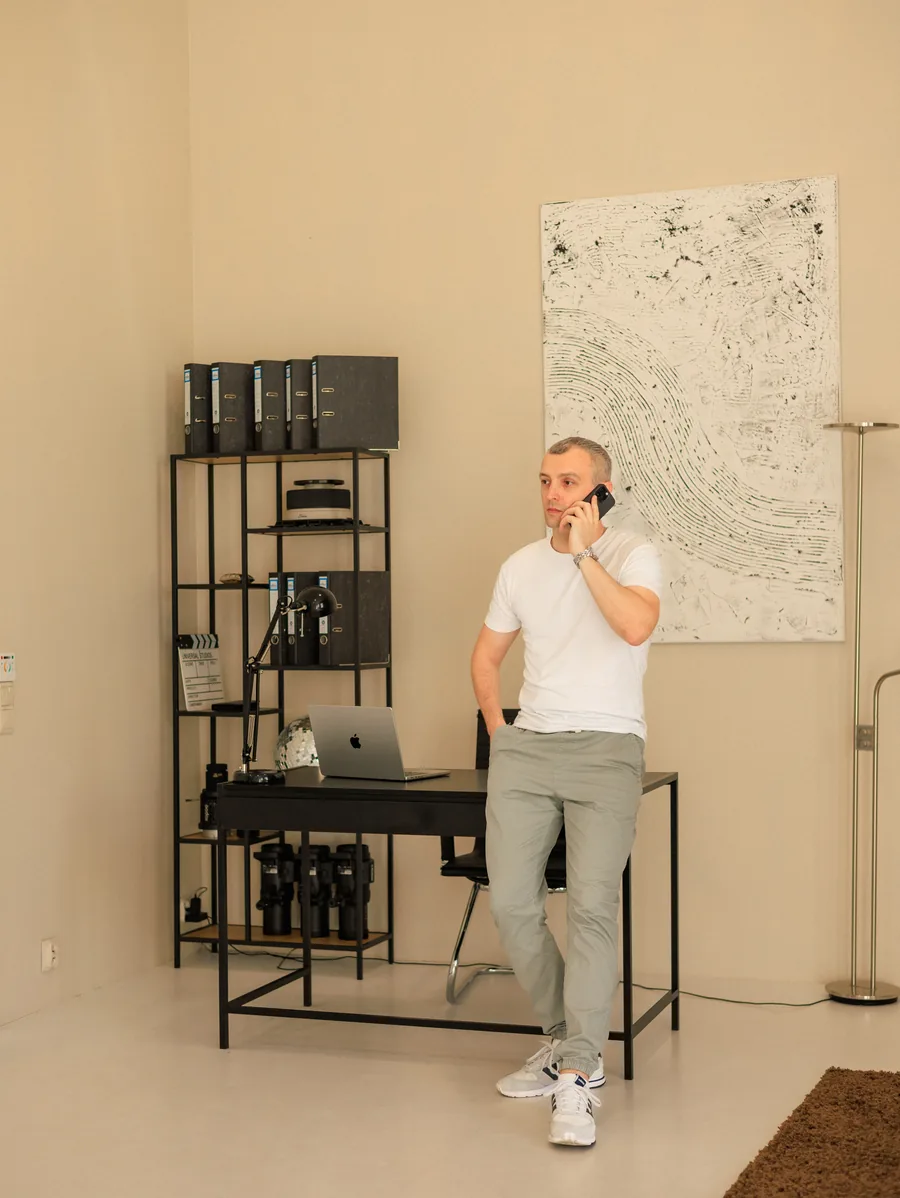 Yaroslav Volkov standing beside a studio desk, talking on the phone.