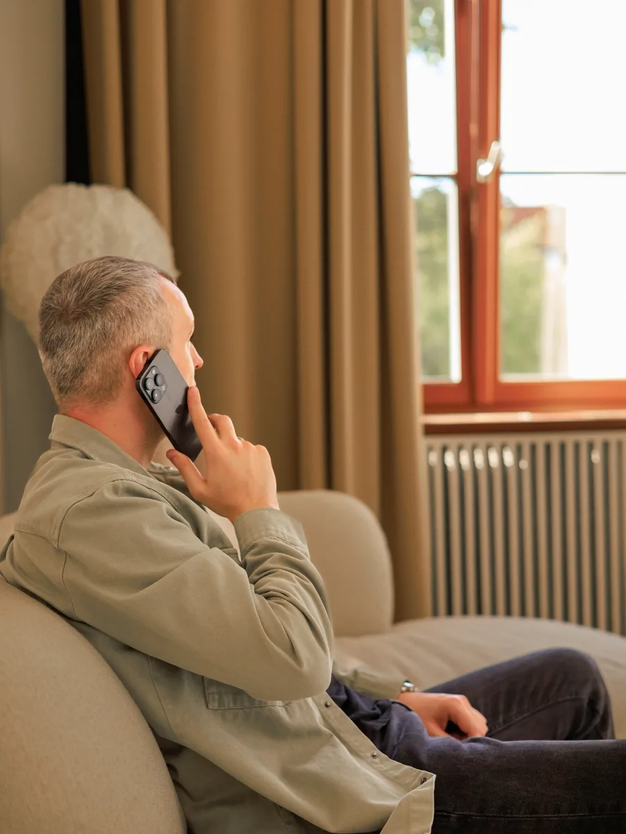 Yaroslav Volkov talking on the phone while sitting beside a studio window.