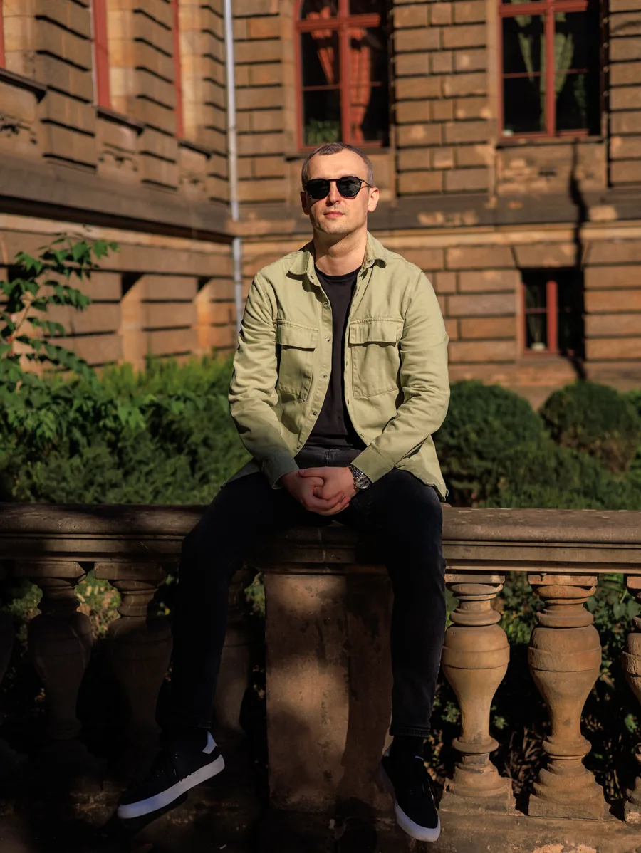 Yaroslav Volkov wearing sunglasses and sitting on a stone balustrade in Wrocław.