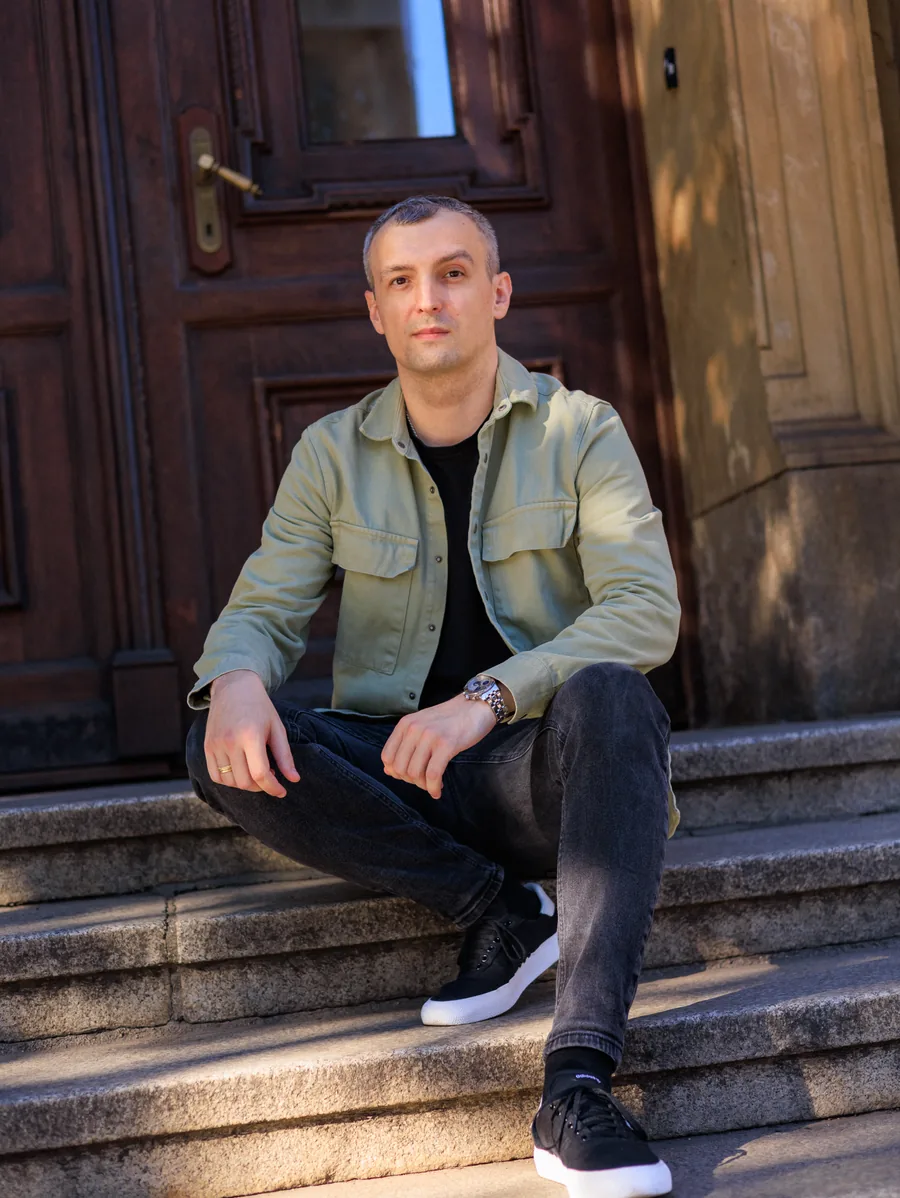 Yaroslav Volkov seated on stone steps in front of a wooden doorway.