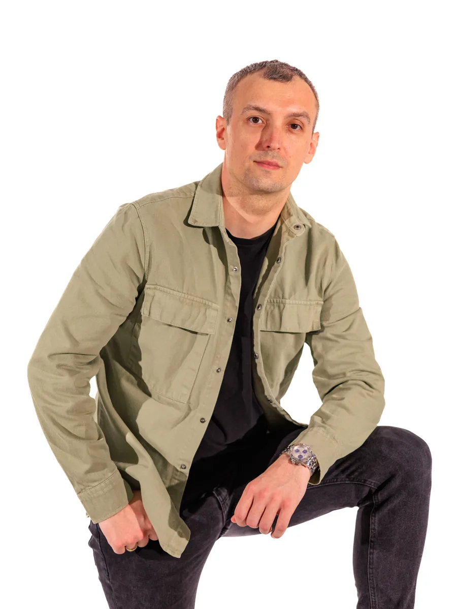 Seated portrait of Yaroslav Volkov wearing a green overshirt over a black T-shirt.